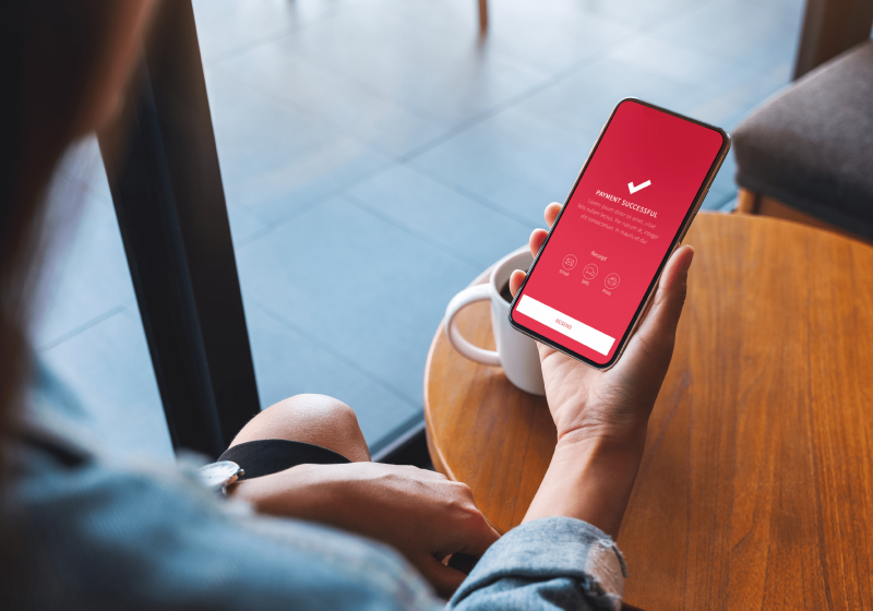 Person holding phone with screen displaying 'payment confirmed'