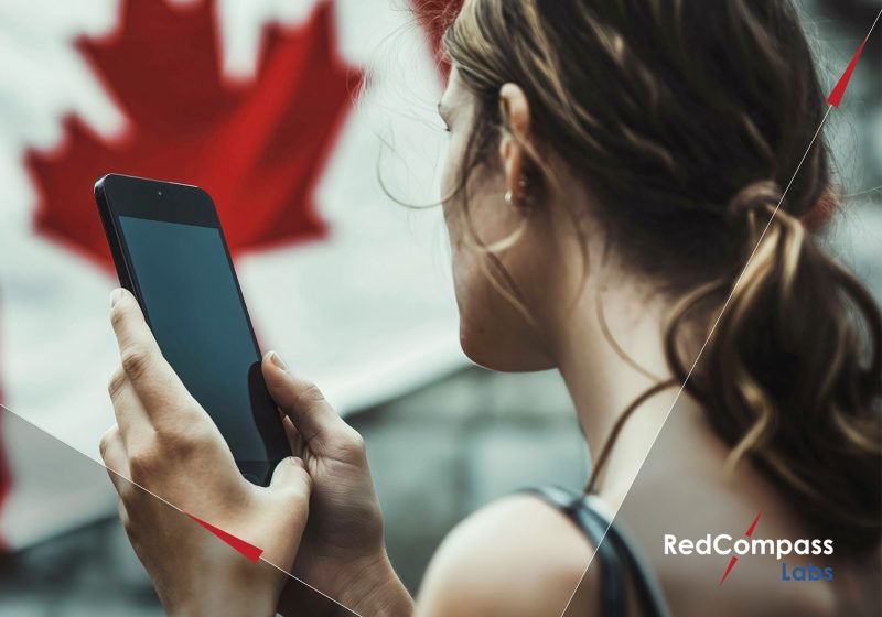 Lady looking at phone with Canadian flag in background
